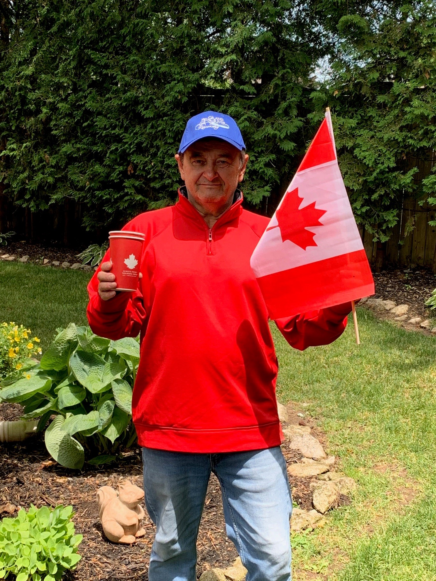 older white man with red sweatshirt, tim horton's cup and canada flag