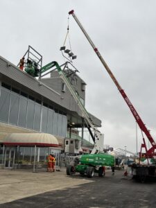 two cranes raise lighting to be installed on the main raceway building