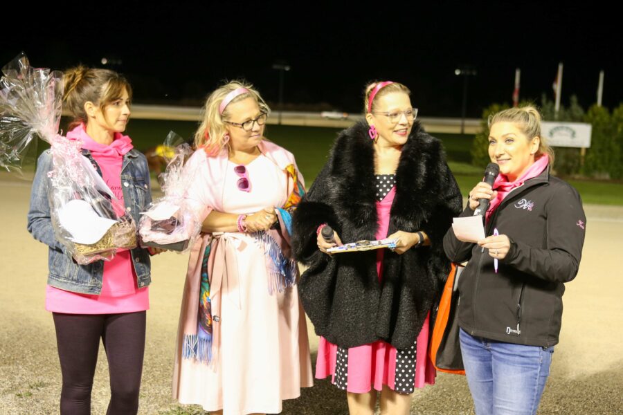 four women in pink one talking on microphone