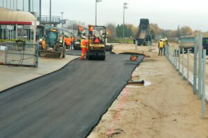 tarmac partially complete using several contruction workers and machinery